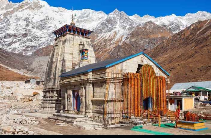 Kedarnath Temple surrounded by snow-capped Himalayan mountains under a clear sky